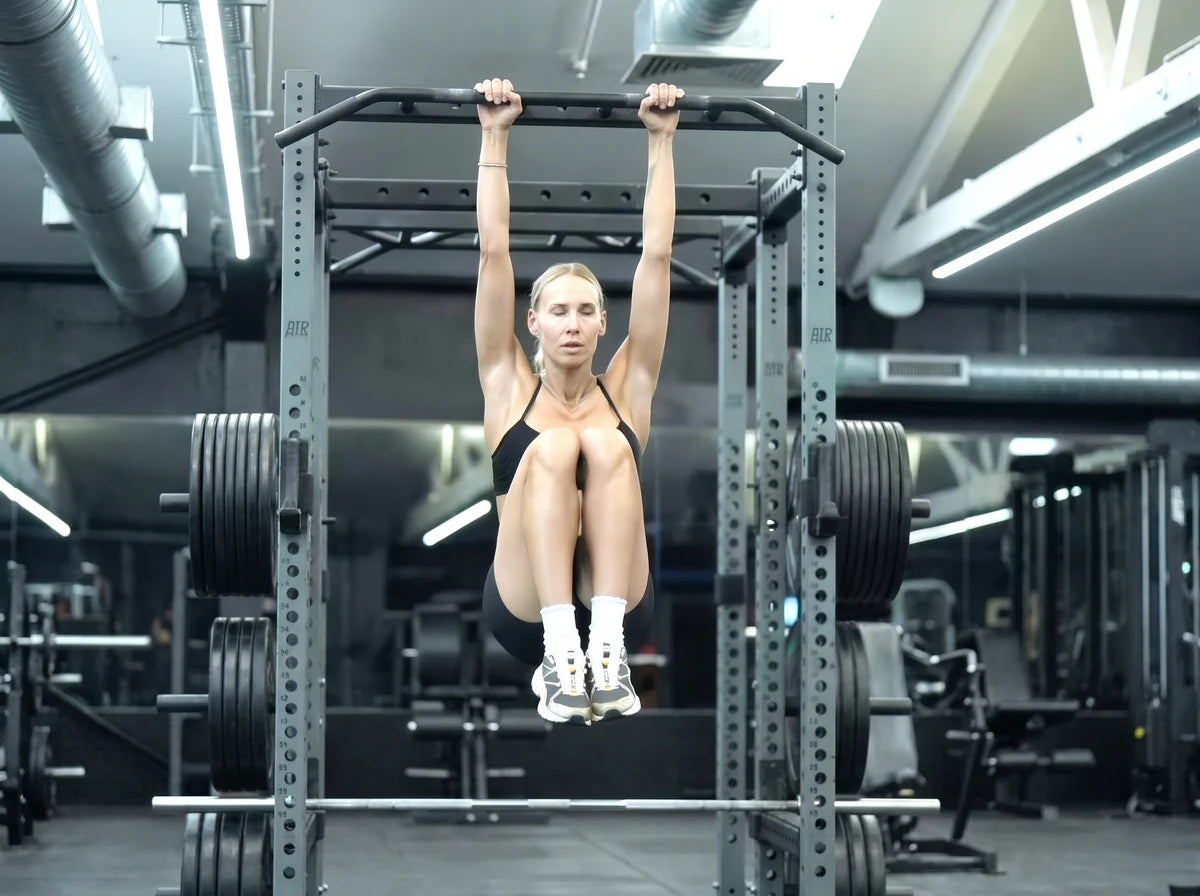 Jonna hanging from a pull-up bar with her knees raised, mid-rep