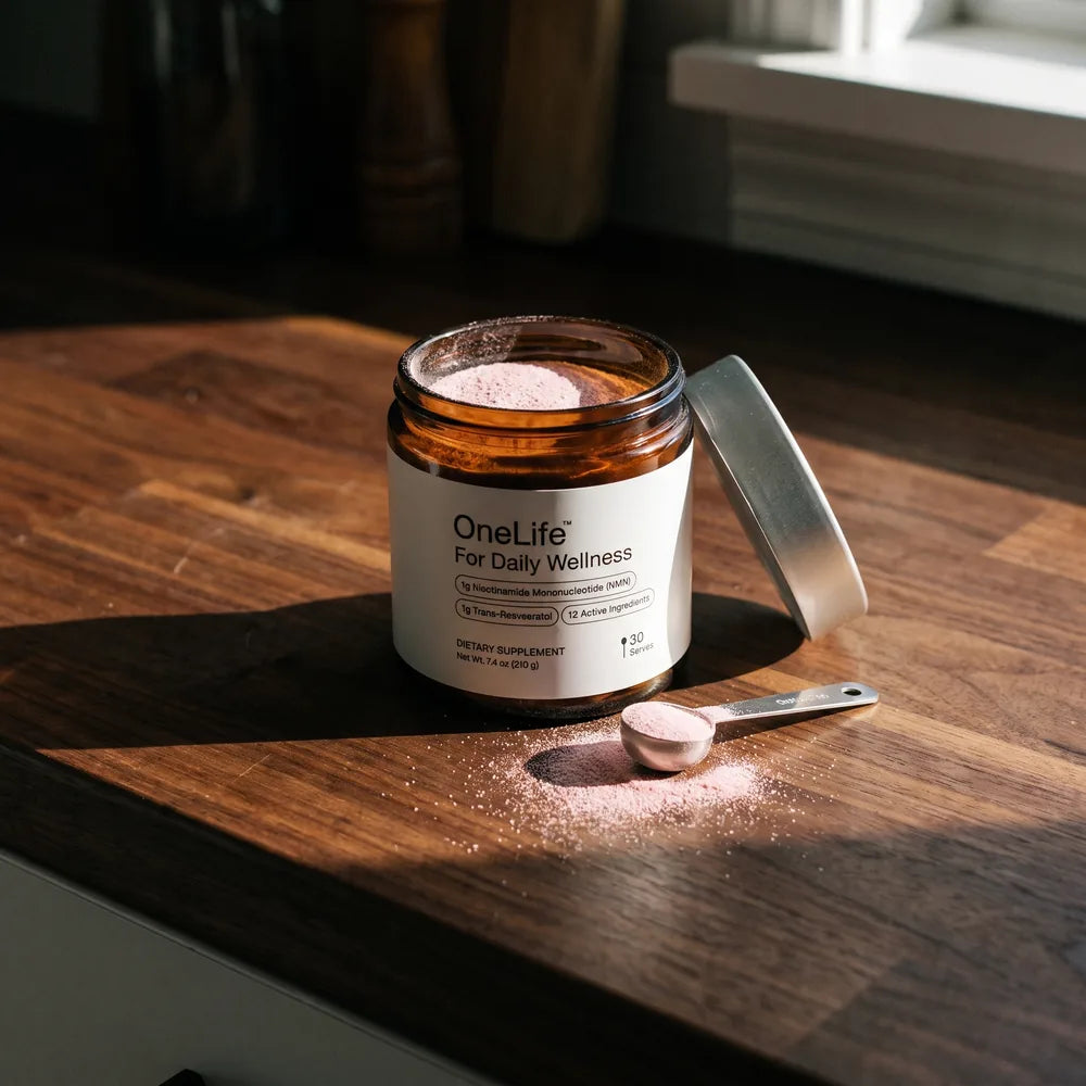 An open OneLife jar on a walnut kitchen bench in hard morning light, its scoop resting beside it
