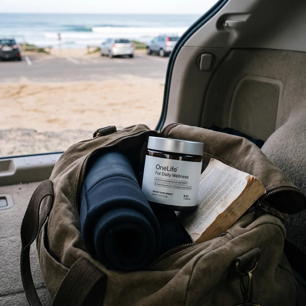 The OneLife jar packed in a canvas duffel beside a rolled wetsuit, in the open boot of a car at the beach