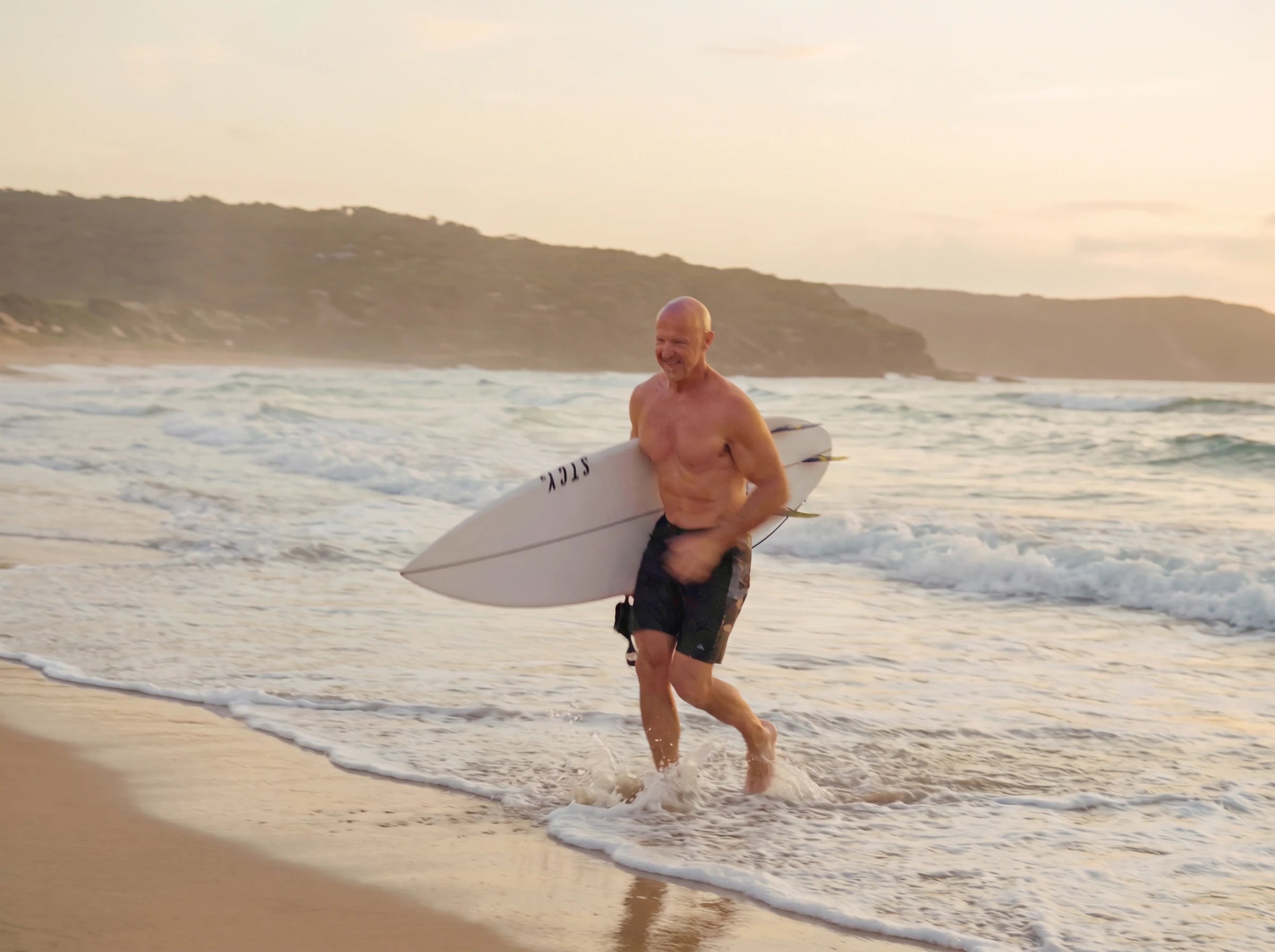 Darren running out of the shore break at first light, his surfboard under his arm