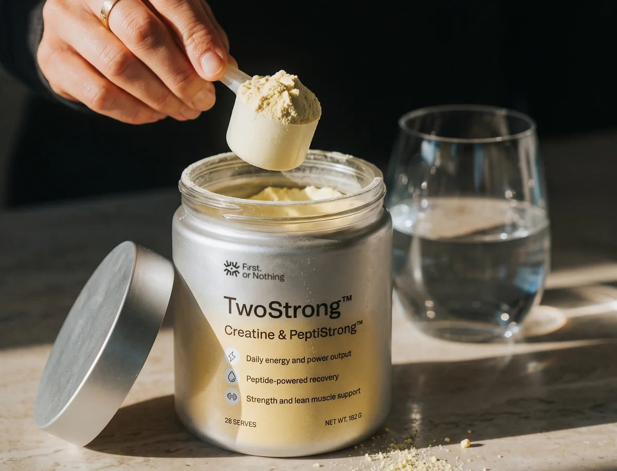 A scoop of TwoStrong lifted from the open jar, a glass of water beside it